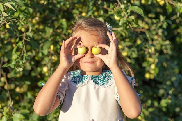 Meisje met appel voor haar gezicht in de appelboomgaard. Mooi meisje biologische appel eten in de boomgaard.