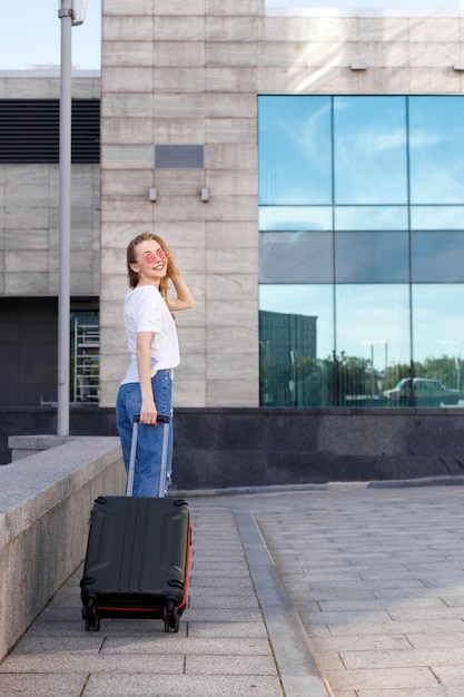 Meisje met bagage in een wit T-shirt op straat in de zomer