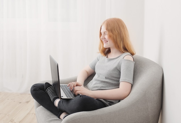 Meisje met behulp van een laptop in fauteuil