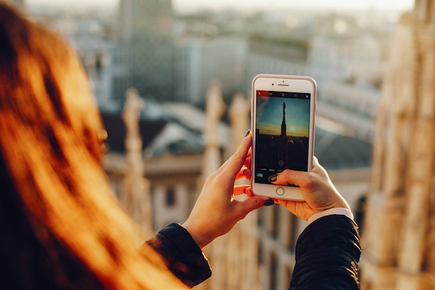 meisje met behulp van haar telefoon tijdens het verkennen van de duomo in Milaan, Italië