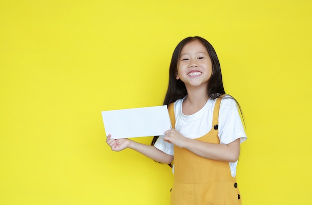 Meisje met blanco vel papier op gele achtergrond