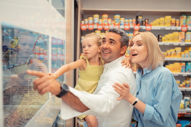 Meisje met blauwe ogen is blij om papegaaien met ouders te zien