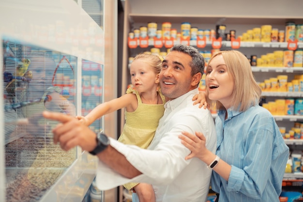 Meisje met blauwe ogen is blij om papegaaien met ouders te zien