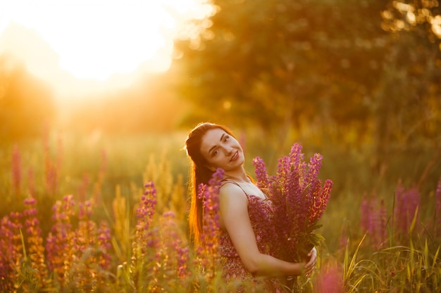 Meisje met bloemen. Brunette in het veld. zonsondergang