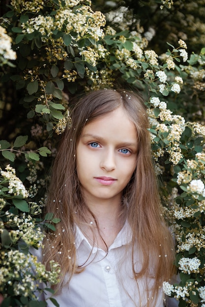 Meisje met bloemen, lang blond haar, close-up portret bloeiende struik. Lente tijd concept.