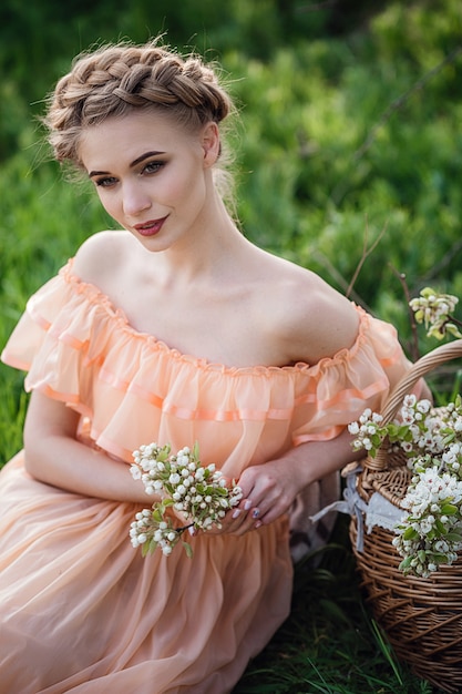 Meisje met blonde haren in een lichte jurk in een bloeiende tuin. concept van vrouwelijke lente mode.