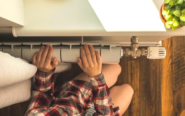 Meisje met blote voeten naast de radiatorverwarming op de achtergrond van het moderne interieur