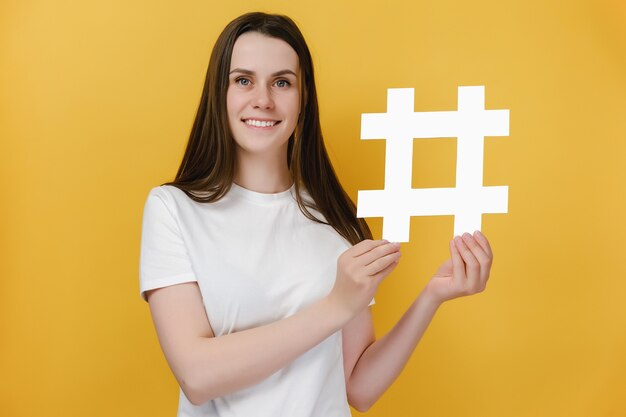 meisje met brede glimlach demonstreert hashtag-symbool