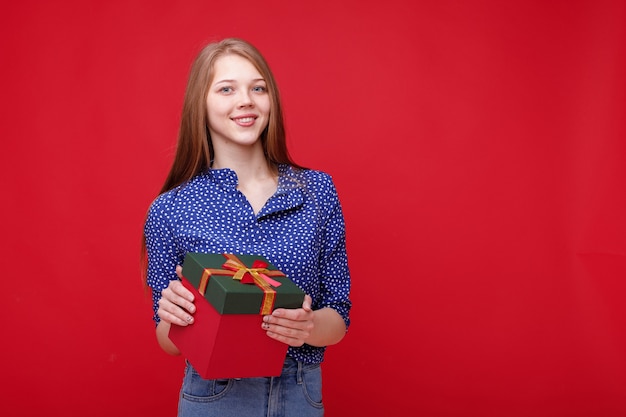 Meisje met cadeau blij op rode achtergrond