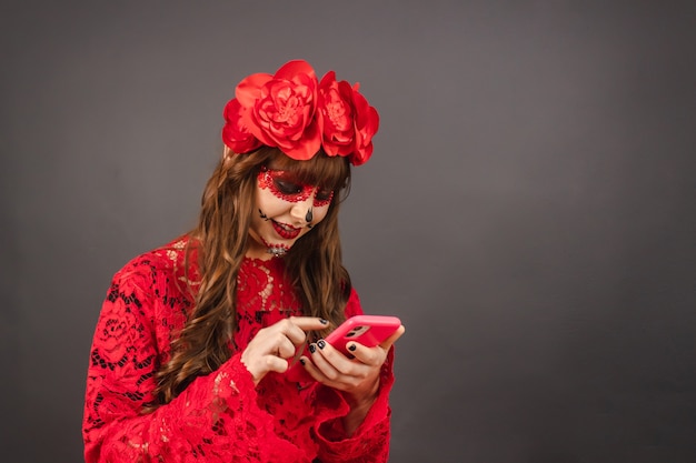 Meisje met Day of the Dead-make-up met behulp van haar smartphone.