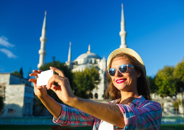 Foto meisje met de hoed die een selfie maakt met de smartphone op de achtergrond van de blauwe moskee istanbul turkije