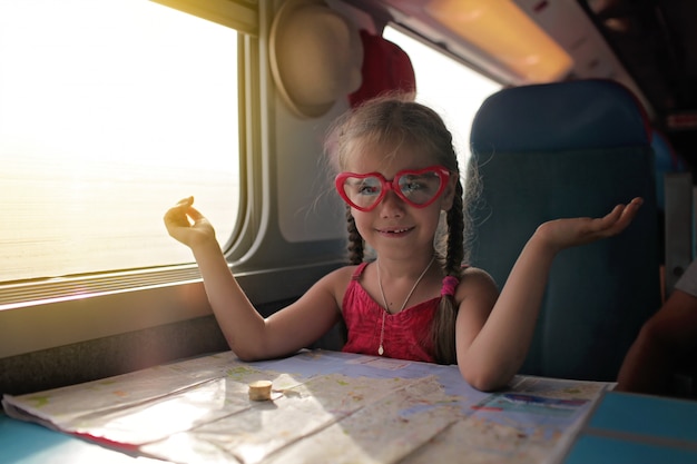 Meisje met de planning van haar economie vakantie tijdens het reizen met de trein