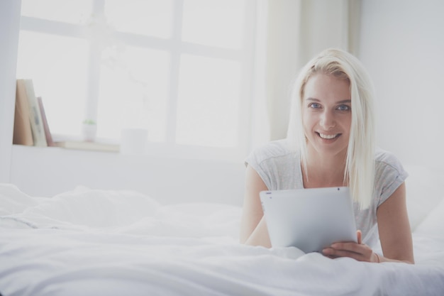 Meisje met digitale tablet met leeg scherm en glimlachend in de camera in de slaapkamer