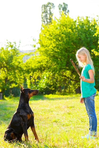 Foto meisje met dobermann in zomerpark.