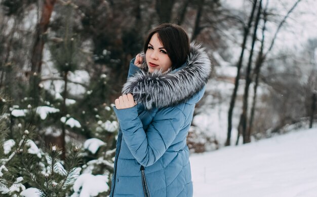 Meisje met donker haar met natuurlijke zilveren vossenbont poseren in een besneeuwd bos.