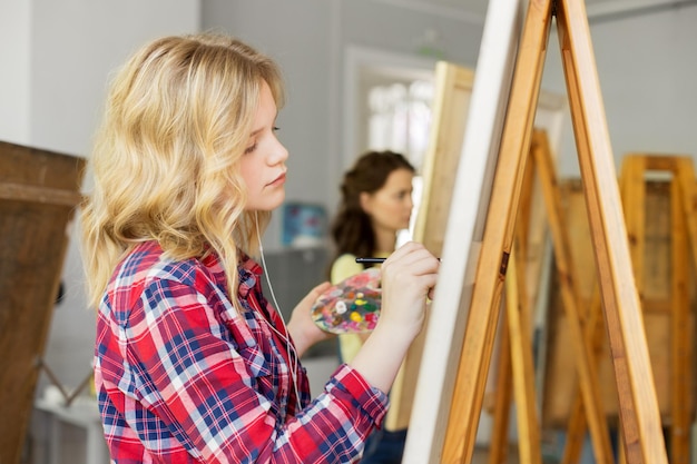 Foto meisje met easel schilderij in kunst school studio