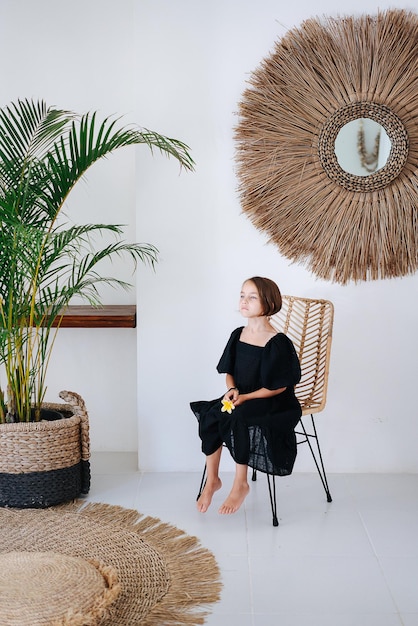 Foto meisje met een bloem die op een stoel zit in het interieur van een zomerhuis