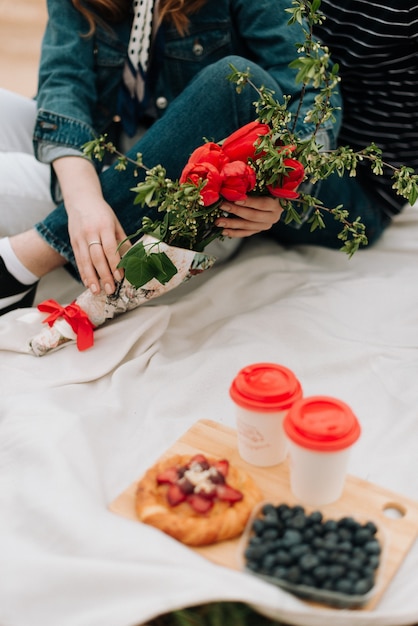 Meisje met een boeket bloemen zit op een witte plaid, zomerpicknick. zomer