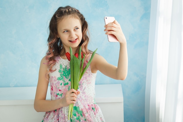 Meisje met een boeket tulpen fotografeert zichzelf telefonisch door haar tong uit te steken.