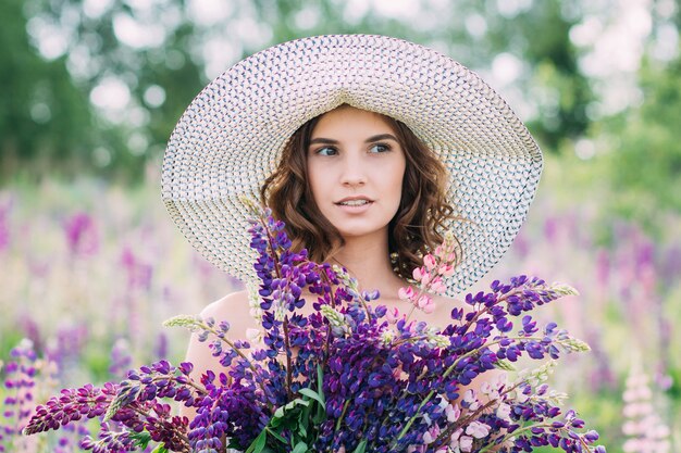 Meisje met een boeket van lupine op het veld