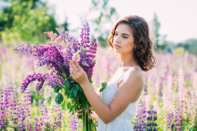 Meisje met een boeket van lupine op het veld