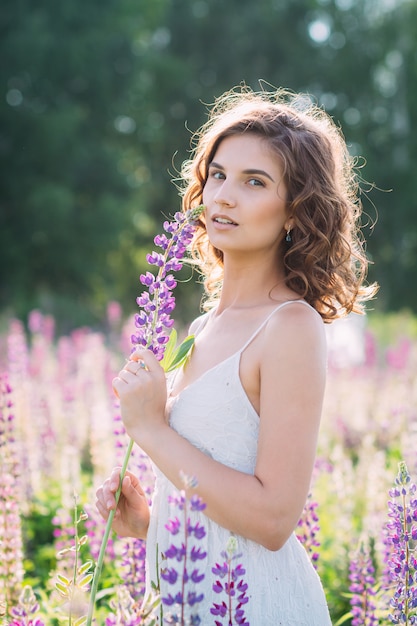 Meisje met een boeket van lupine op het veld