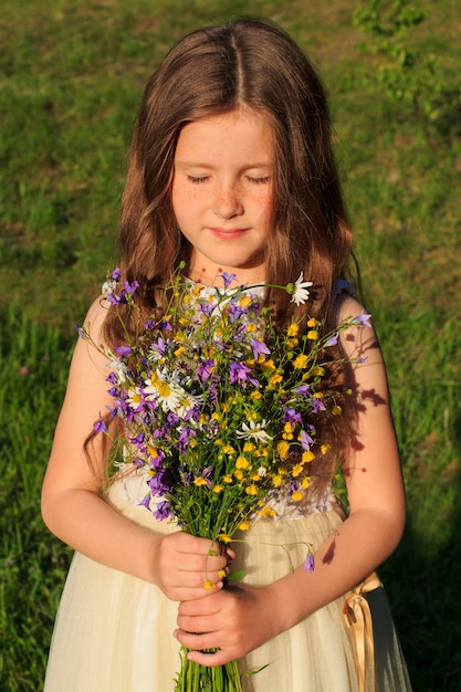 Meisje met een boeket van wilde bloemen en gesloten ogen