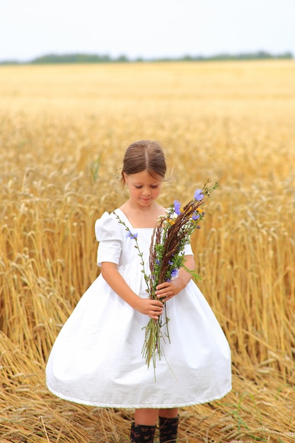 Meisje met een boeket wilde bloemen op het veld