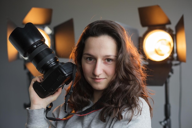 Meisje met een camera in de studio op de achtergrondverlichting hipster fotograaf