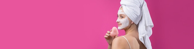 Meisje met een cosmetisch masker op haar gezicht in een witte handdoek