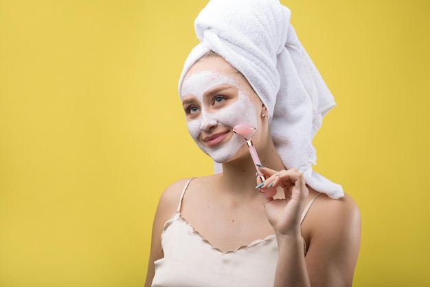 Meisje met een cosmetisch masker op haar gezicht in een witte handdoek.