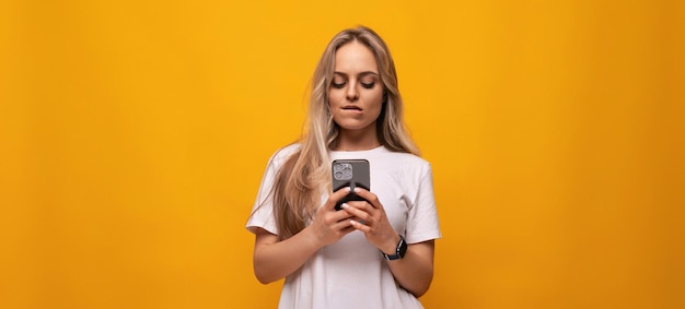 Meisje met een gadget zit op internet op een oranje achtergrond