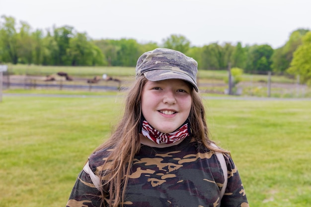 Foto meisje met een glimlach die camouflagekleding en een amerikaans vlagmasker draagt.