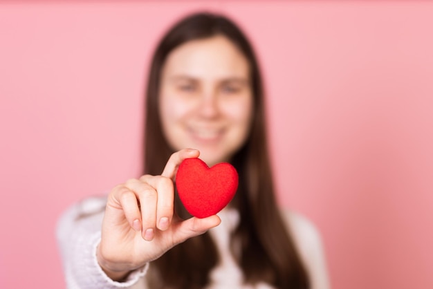 Meisje met een hart in haar handen close-up op een roze achtergrond het concept van valentijnsdag