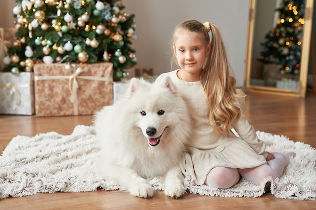 Meisje met een hond in de buurt van de kerstboom op de achtergrond van kerstmis