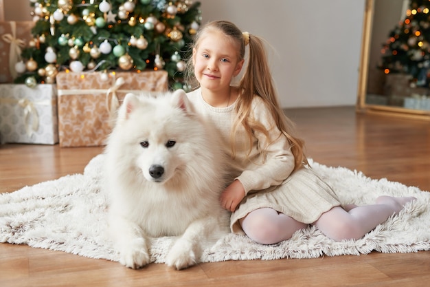 Meisje met een hond in de buurt van de kerstboom