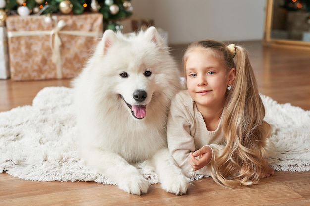 Meisje met een hond in de buurt van de kerstboom