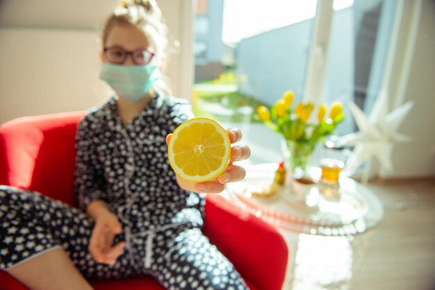 Foto meisje met een masker met citroen thuis.