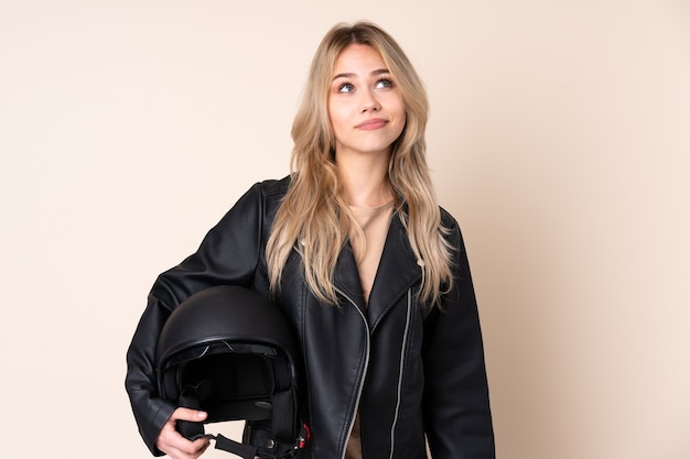 meisje met een motorhelm geïsoleerd op beige en opzoeken