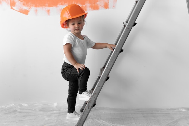 Meisje met een oranje helm op haar hoofd. beklimt de trap Home renovatie concept.