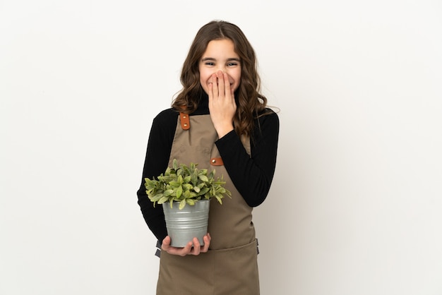 Meisje met een plant geïsoleerd blij en glimlachend bedekkende mond met hand