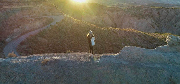 Meisje met een reiscamera bovenop een berg die foto's maakt van het landschap