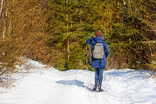 Meisje met een rugzak die zich in een sneeuwbos bevindt.
