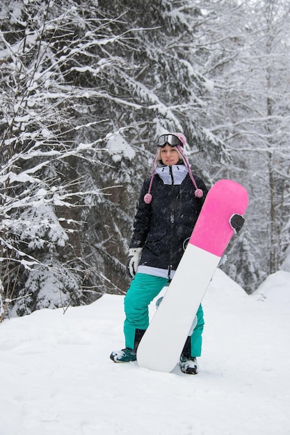 Meisje met een snowboard in het bos in de bergen en de sneeuwval