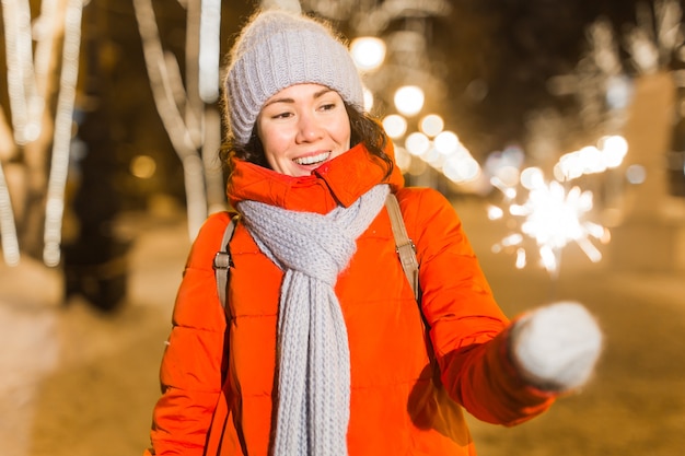 Meisje met een sterretje in haar hand buiten winter stad achtergrond sneeuw sneeuwvlokken