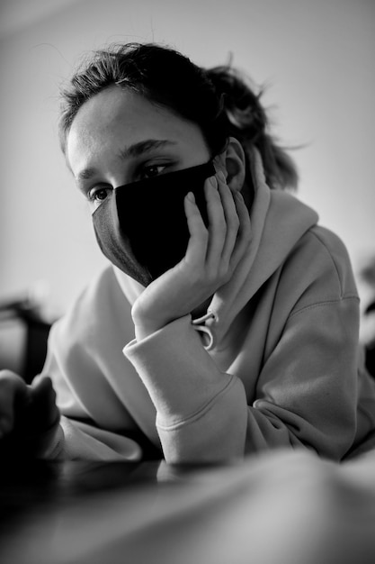 Meisje met een zwart masker werkt thuis op een laptop in isolement zwart-wit foto