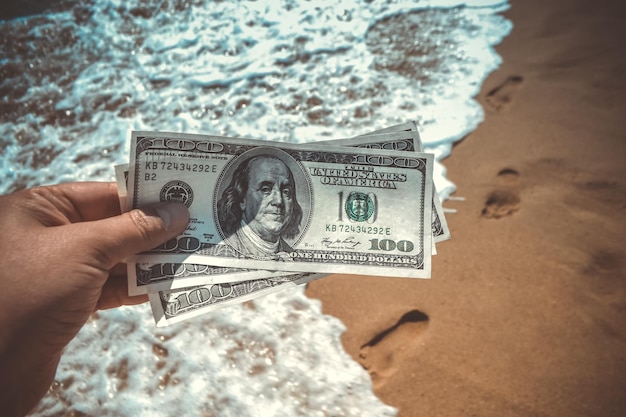 Meisje met geldrekening van 300 dollar op de achtergrond van de zee oceaan