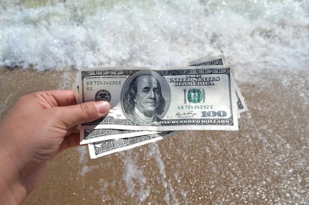 Meisje met geldrekening van 300 dollar op de achtergrond van de zee-oceanen