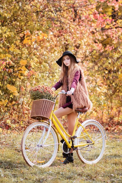Meisje met gele fiets in de herfst op een wandeling.