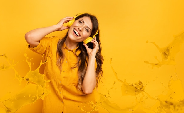 Meisje met gele hoofdtelefoon luistert naar muziek en dansen. emotionele en energieke expressie